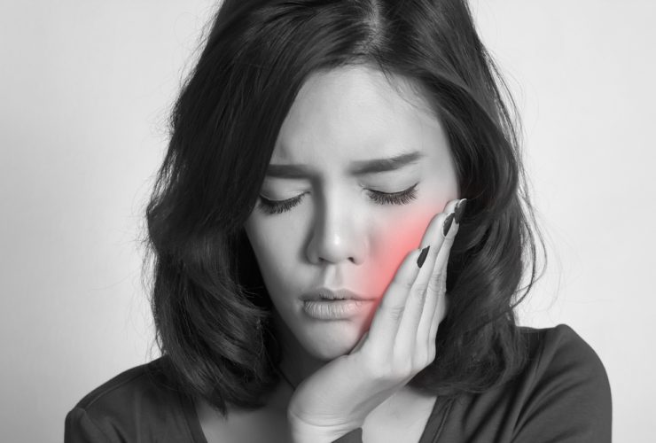 Dolor de muelas. Mujer sujetándose la mejilla con gesto de dolor|Dolor de muelas causado por enfermedad periodontal|Door de muelas provocado por muelas del juicio impactada